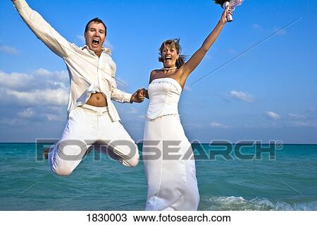 Wedding couple jumping on beach View Large Photo Image Stock Image - Wedding couple jumping on beach. Fotosearch