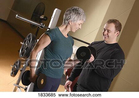 Woman being shown how to lift weights View Large Photo Image Stock Photography - Woman being shown how to lift weights. Fotosearch