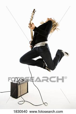 Stock Image - Woman excitedly playing electric guitar. Fotosearch