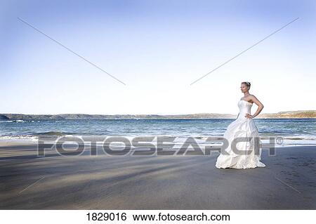 Stock Photograph - Woman in wedding dress on beach. Fotosearch
