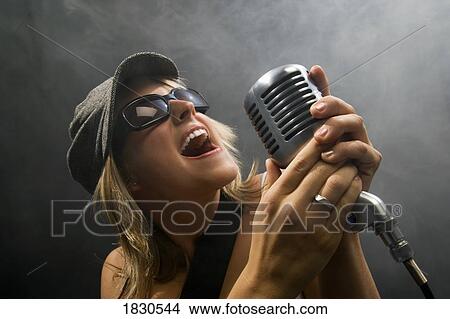 Woman singing in a microphone View Large Photo Image Picture - Woman singing in a microphone. Fotosearch