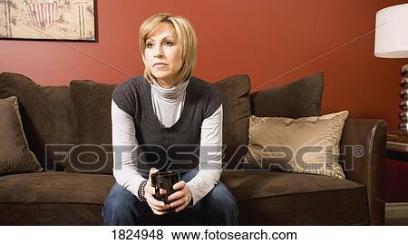 Woman sitting on couch View Large Photo Image Stock Photo - Woman sitting on couch. Fotosearch