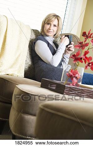 Stock Photography - Woman sitting on sofa. Fotosearch