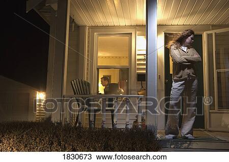 Stock Image - Woman standing outside of her house. Fotosearch