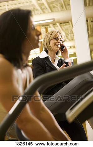 Woman using cell phone on treadmill View Large Photo Image Stock Photography - Woman using cell phone on treadmill. Fotosearch