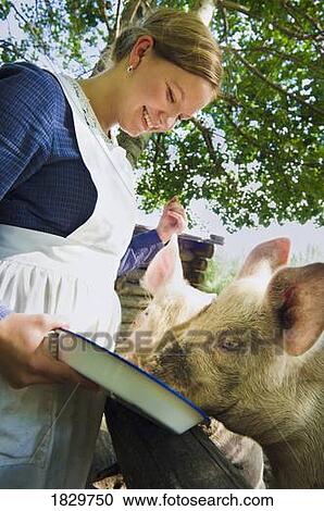 Woman wearing pioneer costume feeding pig, Fort Edmonton, Alberta, Canada View Large Photo Image Stock Image - Woman wearing pioneer costume feeding pig, Fort Edmonton, Alberta, Canada. Fotosearch
