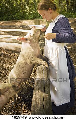 Woman wearing pioneer costume feeding pig, Fort Edmonton, Alberta, Canada View Large Photo Image Stock Photo - Woman wearing pioneer costume feeding pig, Fort Edmonton, Alberta, Canada. Fotosearch