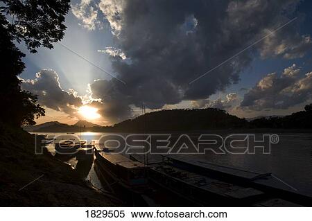 Wooden river boats at sunset along the Mekong River at Luang Prabang, Laos View Large Photo Image Stock Photography - Wooden river boats at sunset along the Mekong River at Luang Prabang, Laos. Fotosearch