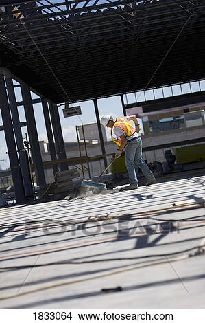 Picture - Worker sweeping at a construction site. Fotosearch