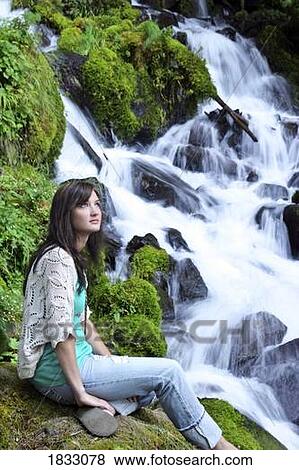 Young girl sitting by a waterfall View Large Photo Image Stock Photo - Young girl sitting by a waterfall. Fotosearch