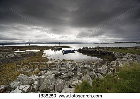 Stock Image - Boat in water and stormy sky. Fotosearch