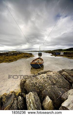 Boat tied to rocks on shore View Large Photo Image Stock Photograph - Boat tied to rocks on shore. Fotosearch