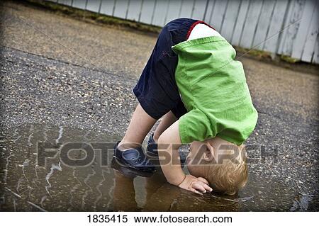 Stock Photography - Boy playing in a rain puddle. Fotosearch