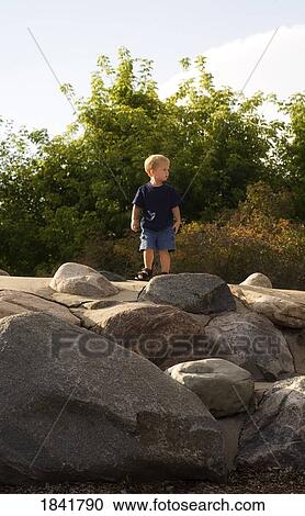 Stock Image - Boy standing on rocks. Fotosearch