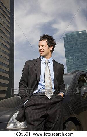 Stock Image - Businessman standing in front of car. Fotosearch