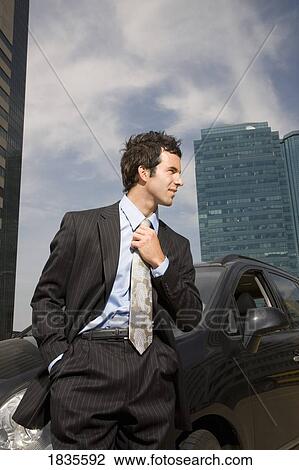 Stock Image - Businessman standing in front of car. Fotosearch