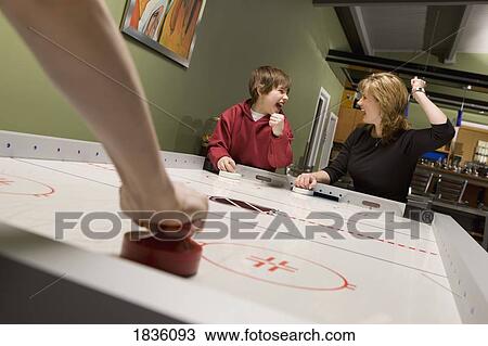 Stock Image - Family playing air hockey. Fotosearch