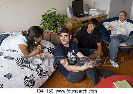 Stock Image - Friends relaxing in dorm room. Fotosearch