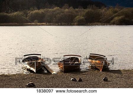 Stock Photo - Lake District, Cumbria, England; three rowboats on shore. Fotosearch