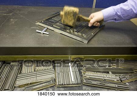 Stock Image - Letterpress printing; levelling type with mallet. Fotosearch