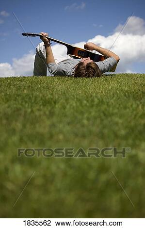 Man playing guitar on the grass View Large Photo Image Stock Image - Man playing guitar on the grass. Fotosearch