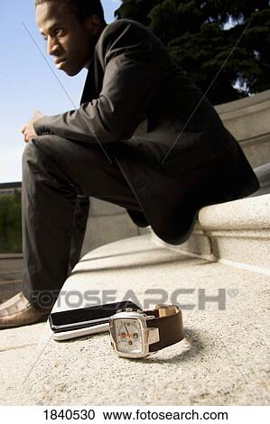 Man sitting on steps with watch and phone on the ground View Large Photo Image Stock Image - Man sitting on steps with watch and phone on the ground. Fotosearch