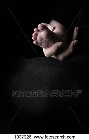 Stock Photograph - Mother's hand holding baby's foot . Fotosearch