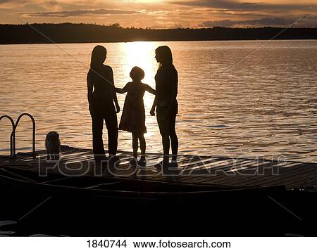 Silhouette of three females on a dock, Lake of the Woods, Ontario, Canada View Large Photo Image Picture - Silhouette of three females on a dock, Lake of the Woods, Ontario, Canada. Fotosearch