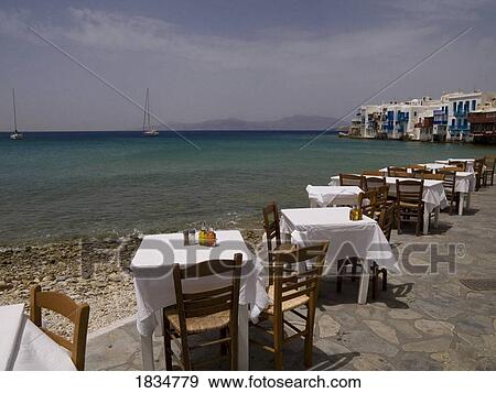 Stock Photo - Tables and chairs with an ocean view, Greek Islands, Greece. Fotosearch