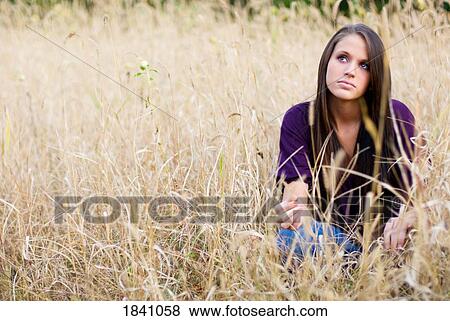 Teen girl sitting in tall grass View Large Photo Image Stock Photo - Teen girl sitting in tall grass. Fotosearch