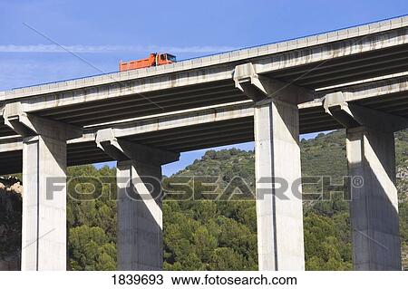 Stock Image - Truck crossing ravine on highway bridge . Fotosearch