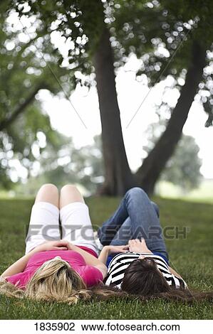 Stock Image - Two girls laying on the grass. Fotosearch