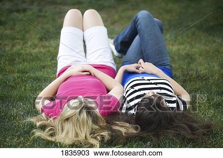 Two girls laying on the grass View Large Photo Image Stock Image - Two girls laying on the grass. Fotosearch