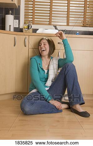 Stock Photography - Woman laughing on the floor of the kitchen. Fotosearch