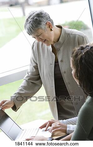 Picture - Woman looking at laptop with others. Fotosearch
