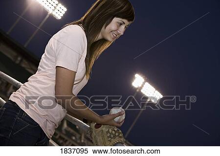 Stock Photography - Young adult woman pitching at a baseball game. Fotosearch