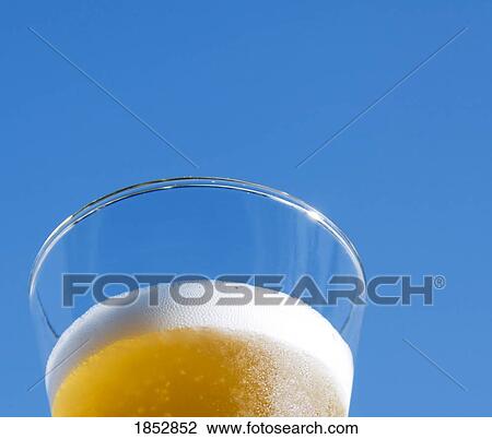 Stock Image - Beer; Beer in glass against blue sky . Fotosearch