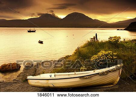 Stock Image - Boat on the shore at sunset, Island of Islay, Scotland. Fotosearch