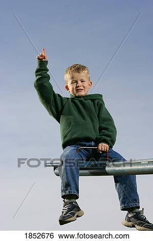 Stock Photograph - Boy on a seesaw; Boy pointing to the sky. Fotosearch