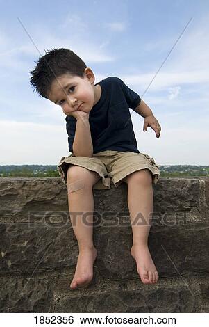Boy sitting on rock wall; Sad boy with bandage View Large Photo Image Stock Photograph - Boy sitting on rock wall; Sad boy with bandage. Fotosearch