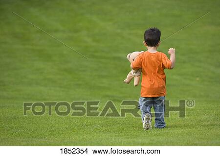Boy with bear; Boy running on grass View Large Photo Image Picture - Boy with bear; Boy running on grass. Fotosearch