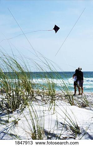 Stock Image - Bradenton Beach, Florida, United States; couple flying a kite on the beach. Fotosearch