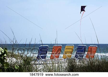 Stock Photo - Bradenton Beach, Florida, USA; Beach chairs lined on beach and a kite flying. Fotosearch