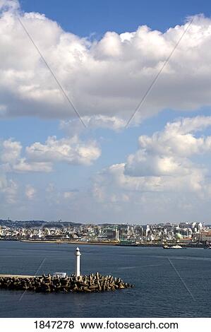 Stock Photo - Breakwater Lighthouse, Naha, Okinawa Island, Japan; Lighthouse with city in the background . Fotosearch