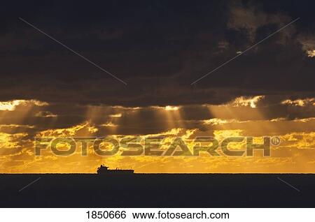 Stock Photograph - Cargo Ship, Atlantic Ocean; Ship silhouetted in the distance in the ocean. Fotosearch
