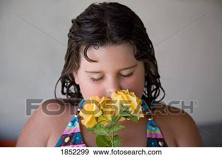 Stock Photo - Child and flowers; Girl smelling the yellow roses. Fotosearch