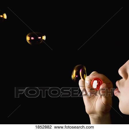 Stock Image - Child blowing bubbles; Young Boy blowing bubbles. Fotosearch