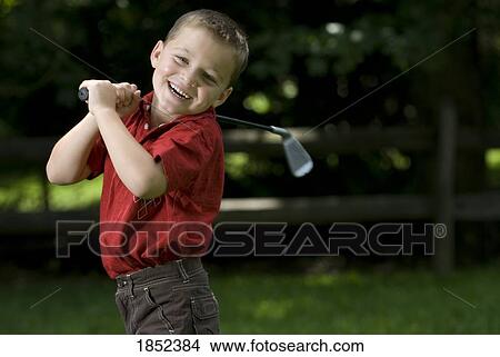 Picture - Child having fun; Boy practicing his golf swing. Fotosearch