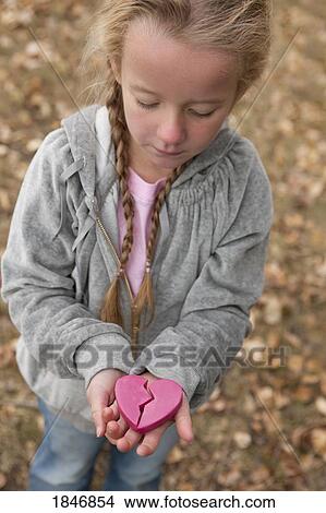 Picture - Child holding a broken heart. Fotosearch