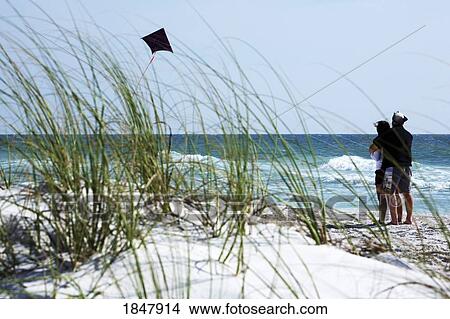 Picture - Couple; Flying a kite on the beach. Fotosearch